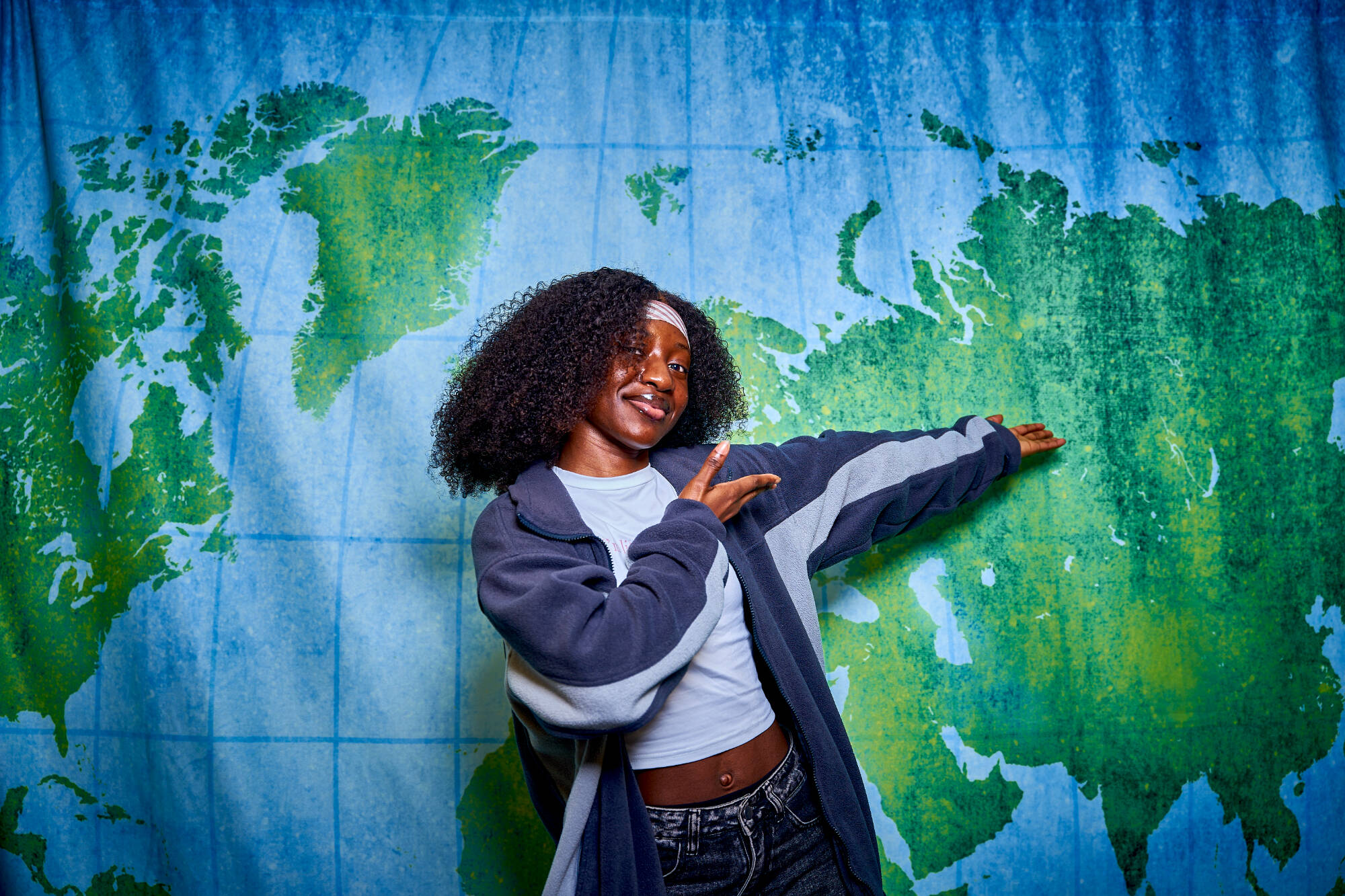 student pointing to world map behind her